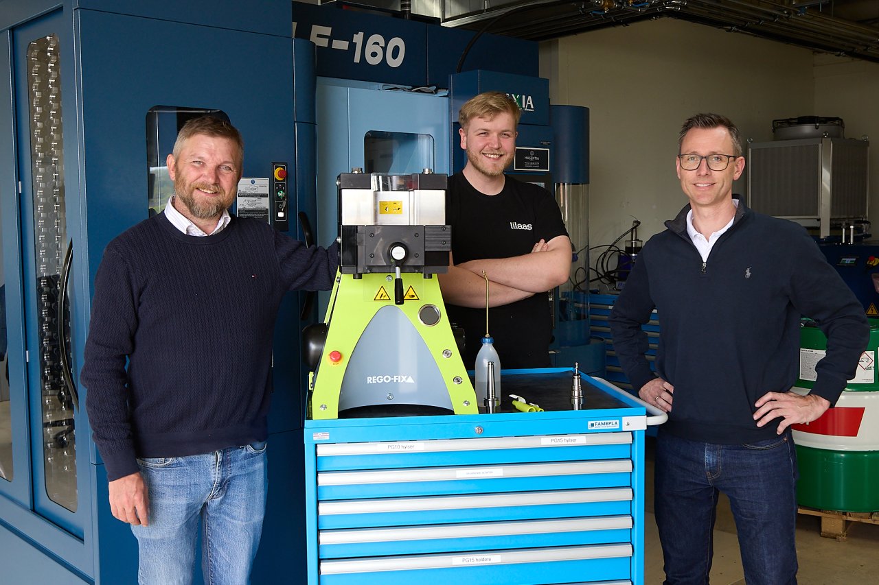 Tre menn foran en CNC maskin for makinering